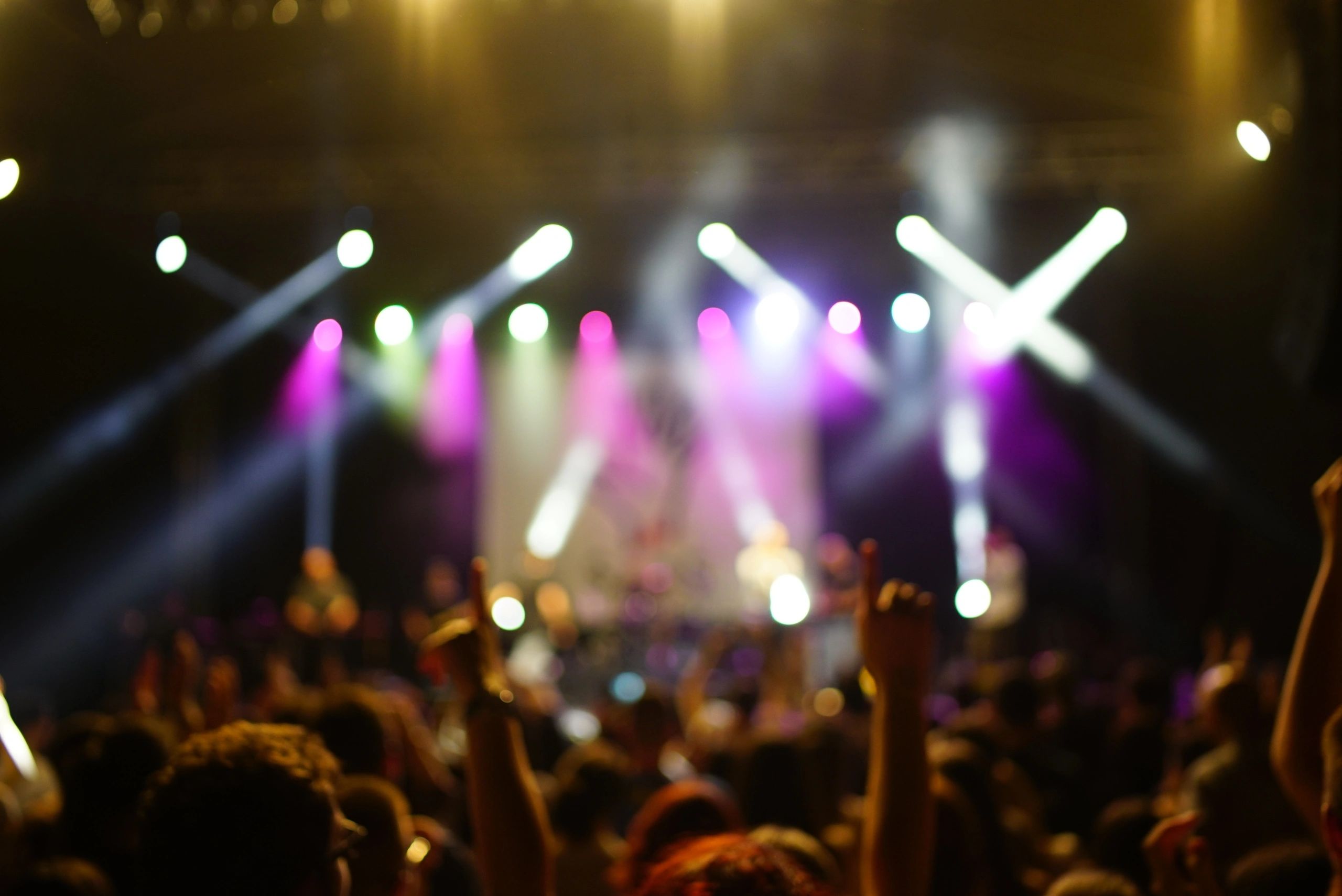 Crowd with raised hands in a hopeful concert setting